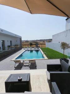 a swimming pool with chairs and a table at DH Country House in Évora