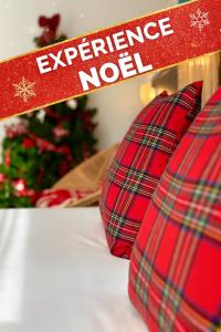 Ein Schild mit der Aufschrift „Erleben Sie Weihnachten“ neben einem Weihnachtsbaum in der Unterkunft The Originals City, Hotel Cap Maya, Cap d'Agde in Cap d'Agde