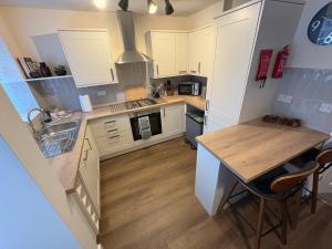 eine Küche mit weißen Schränken und einem Holztisch in der Unterkunft Greenfield House - Keighley Eastburn in Kildwick + 6 Fotos