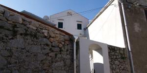 a white building with a stone wall and an archway at Mariana B4 in Veli Lošinj