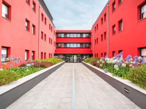 eine Gasse zwischen zwei roten Gebäuden mit Blumen in der Unterkunft Hotel Ibis Lisboa Sintra in Sintra