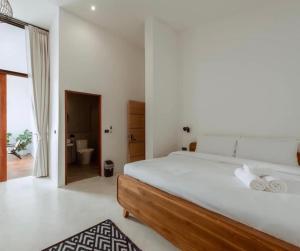 a white bedroom with a large bed and a bathroom at Radda Sea House in Ko Larn