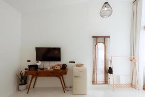 a room with a refrigerator and a table with a tv at Radda Sea House in Ko Larn