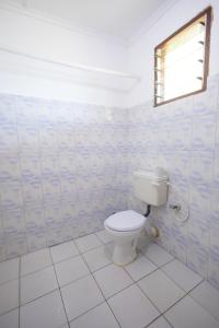 a bathroom with a toilet and a window at Kash apartments in Diani Beach