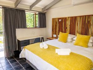 a bedroom with a large bed with yellow pillows and a desk at House 1967 in George