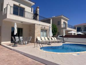 波利斯Villa Merope Irena 2的房子旁边有带椅子和遮阳伞的游泳池