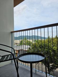 a chair and a table on a balcony with a view at Wora Phuket in Ban Sam Kong
