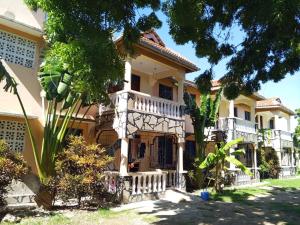 a large yellow house with a white balcony at Kash apartments in Diani Beach