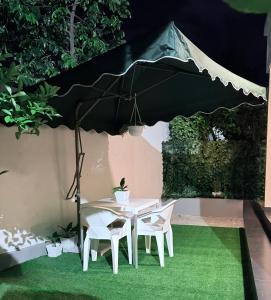 a white table and chairs under a black umbrella at Blesauz Apartments in Dar es Salaam
