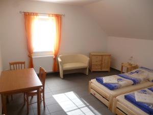 a bedroom with two beds and a table and a chair at Penzion Na Podlesí ve Zlaté Koruně in Zlatá Koruna