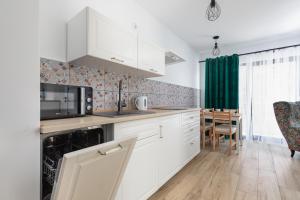 米泽德沃兹Little Laguna Apartments SPA & Gym by Noclegi Renters的配有白色橱柜和微波炉的厨房