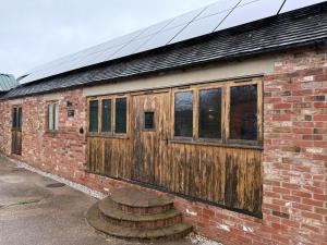 a brick building with a wooden door on it at New House Barn in Ashbourne