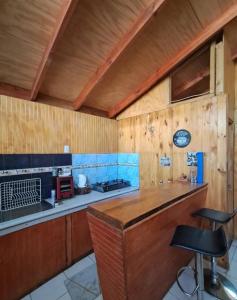 een keuken met houten wanden en een aanrecht met krukken bij Cabañas Armerillo in Colbún Alto