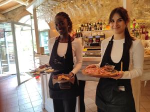 two women standing in a kitchen holding a plate of food at Mulino Di Quercegrossa in Quercegrossa +143 photos