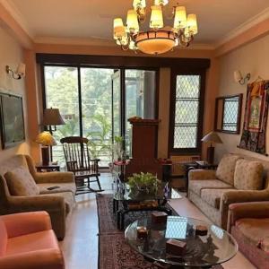 Dr Balis Bliss Homestay Sarvodya Enclave في Jāmb: غرفة معيشة مليئة بالاثاث والثريا