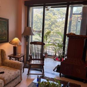 Dr Balis Bliss Homestay Sarvodya Enclave في Jāmb: غرفة معيشة مع كرسي هزاز ونافذة كبيرة