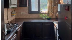 Dr Balis Bliss Homestay Sarvodya Enclave في Jāmb: مطبخ مع موقد وثلاجة