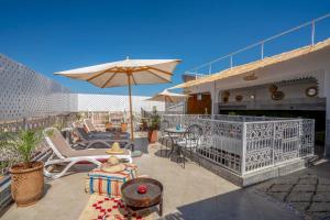 a patio with chairs and an umbrella on a balcony at Riad HAFSSA & Spa in Marrakech
