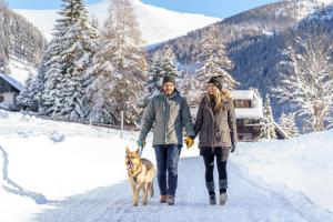 dos personas paseando a un perro en la nieve en Thermenwelt Hotel Pulverer, en Bad Kleinkirchheim 83 fotos más