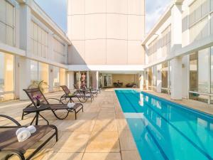 ein Hallenbad mit Liegestühlen neben einem Gebäude in der Unterkunft Mercure Guarulhos Aeroporto in Guarulhos