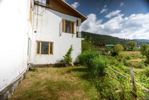 a white house with a window on the side of it at Luxury KA Villa - BIR in Bīr