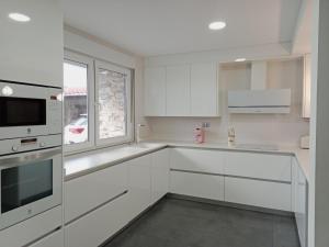 a white kitchen with white cabinets and a window at Villa Abril 56 in Oreña