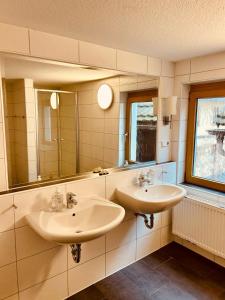 a bathroom with two sinks and two mirrors at Pension Mimosa in Rust +142 photos