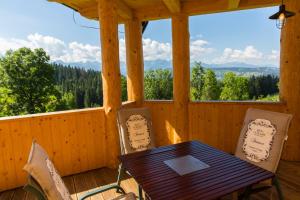 a wooden porch with a wooden table and chairs at udanypobyt Dom Forest Prestige House in Rzepiska