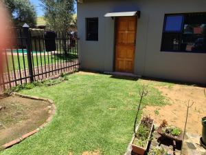 een tuin met een hek, een deur en gras bij Mvuli haven in Pretoria