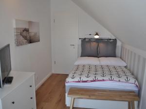 Un dormitorio pequeño con una cama y un televisor. en The House of Port Haf 2, en Niendorf 24 fotos más