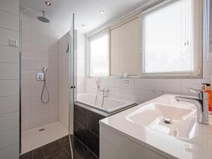 Un baño blanco con lavabo y ducha. en Lovely villa on the edge of the forest, en Westermient 19 fotos más