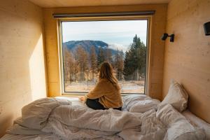 a woman sitting on a bed looking out a window at Rallentare immersi nel verde di Cima Lan  +2 photos