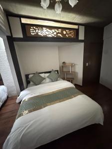 a bedroom with a large white bed and a window at MARU KIX House in Izumi-Sano