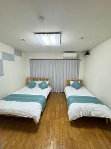 two beds in a room with wooden floors at MARU KIX House in Izumi-Sano
