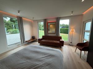 una camera da letto con un letto, un divano e finestre di Beach House in Ardennes a Chaudfontaine