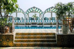 a pool with blue and white furniture and plants at Soho House Mumbai in Mumbai