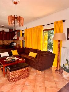 un soggiorno con divano marrone e tende gialle di Jasmine place a Kalamáta