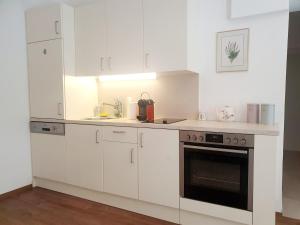 a white kitchen with white cabinets and an oven at BohoNest Mariatrost - Erdgeschoss, Basilika kostenloser Parkplatz in Größing