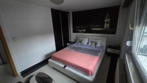 a small bed in a small room with a clock tower at Tvrdjava Apartman in Petrovaradin