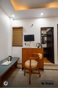 a room with a desk and a chair and a television at Sagar Niwas in New Delhi