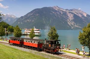 un treno sui binari vicino a un corpo idrico di Haus Christlum ad Achenkirch