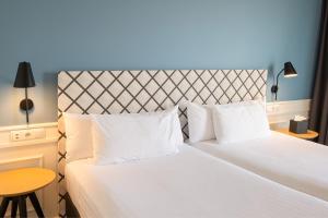 una camera da letto con un letto con lenzuola e cuscini bianchi di Dorma Sardinero a Santander