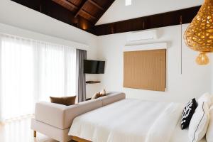 ein Schlafzimmer mit einem weißen Bett und einer Couch in der Unterkunft Villa Nevaeh - Ocean Front Private Villa Kamala Beach in Phuket