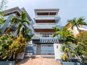 an apartment building with palm trees in front of it at The Infinity Pool Villa Hotel by DanCenter, Baga Beach, Goa in Arpora