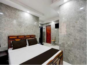 ein Schlafzimmer mit einem Bett und einer Steinwand in der Unterkunft Hotel O Tiruvallur Bus Terminal Formerly SK Vinoth Mahal in Tiruvallūr