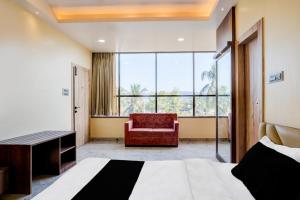 a bedroom with a bed and a chair and a window at Super Townhouse Bhangagarh Bus Terminal Formerly The Rudra Inn in Guwahati