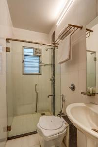 a bathroom with a shower and a toilet and a sink at Hotel Orchard Nest - Pune Sinhgad Road in Pune