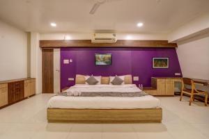 a bedroom with a large bed with a purple wall at Hotel Orchard Nest - Pune Sinhgad Road in Pune
