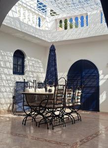 a table and chairs in a room with a patio at Riad Diaz Taghazout in Taghazout