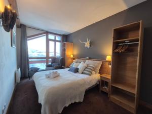 a bedroom with a bed with a chair and a window at Élégant Duplex - Sainte Foy Station - 10 pers in Sainte-Foy-Tarentaise